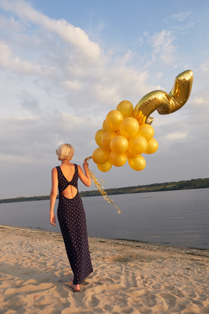 Young woman with many golden balloons.の写真素材