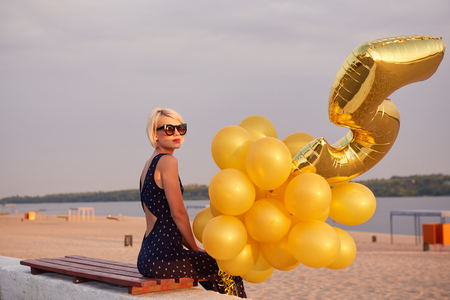 Young woman with many golden balloons.の写真素材