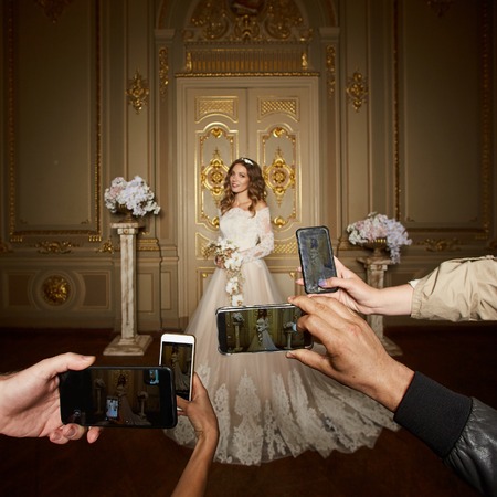 Guests take photographs of the bride on smartphones. Focus on smartphones.の写真素材