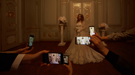 Guests take photographs of the bride on smartphones. Focus on smartphones.の写真素材