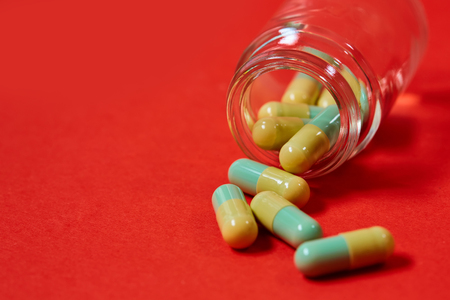 Pills spilling out of pill bottle on red. Top view with copy space.の写真素材