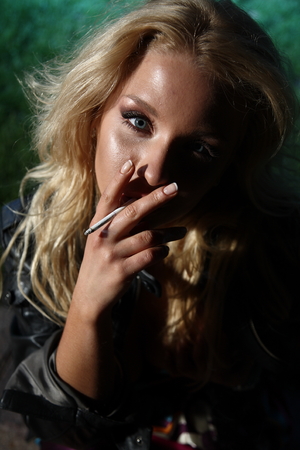 Young woman smoking in night parkの写真素材