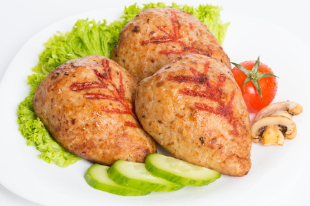 Three fried breaded cutlet with lettuce, tomatoes, cucumbers and mushrooms on white background