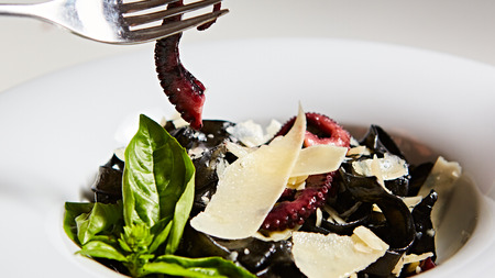 Pasta with black cuttlefish ink, octopuses and parmesan.の写真素材
