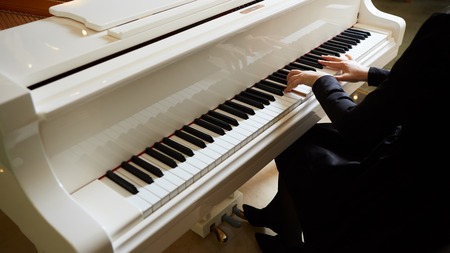 Womans hands on the keyboard of the piano closeupの写真素材