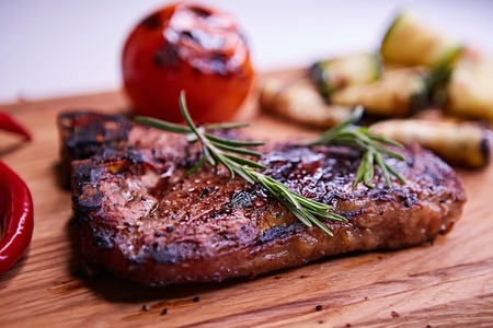 Grilled T-Bone Steak on serving board on wooden backgroundの写真素材