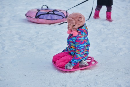 little girl riding on snow slides in winter time