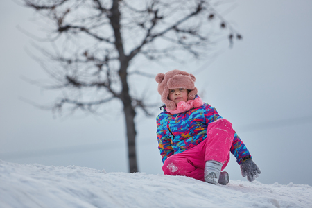 little girl riding on snow slides in winter timeの写真素材