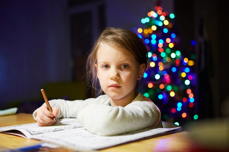 Inspired little girl at the table draw with crayons or do home workの写真素材