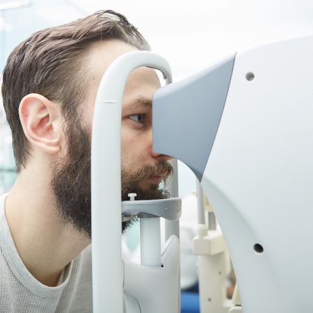 Handsome young man is checking the eye vision in modern ophthalmology clinic. Patient in ophthalmology clinic.の写真素材