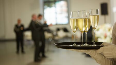 A tray with three glasses of champagne. Waiter holding a tray with a champagne glassの写真素材
