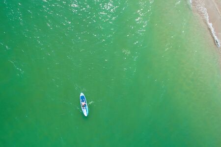 Young woman paddling on SUP board on the tropical beach. Active summer vacations with paddle board.の写真素材