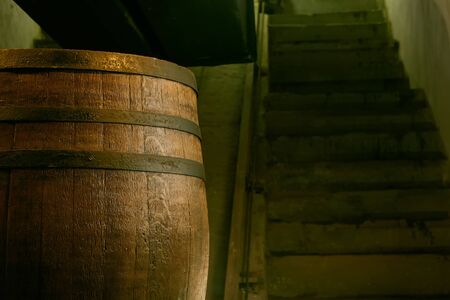 wooden barrel on a dark background, in a workshop, in an old room. production of barrels for cognac and wine, in a low keyの写真素材