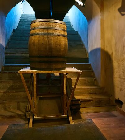 wooden barrel on a dark background, in a workshop, in an old room. production of barrels for cognac and wine, in a low key.の写真素材