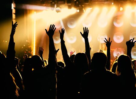 silhouettes of concert crowd in front of bright stage lights.の写真素材