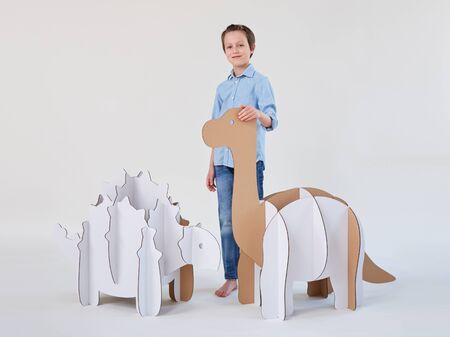 Little dreamer boy playing with a cardboard dinosaurs Brontosaurus and Ankylosaurus. Childhood. Fantasy, imagination.の写真素材