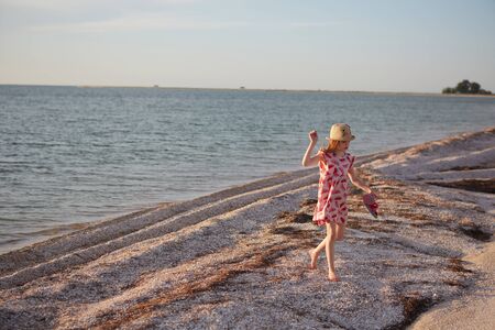 Smiling beautiful girl having fun on the beach. Portrait of happy cute little girl with copy space. Portrait of kid during summer.の写真素材