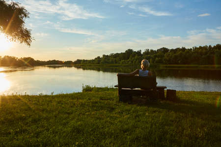 Woman Sitting On Bench During A Beautiful Sunsetの写真素材