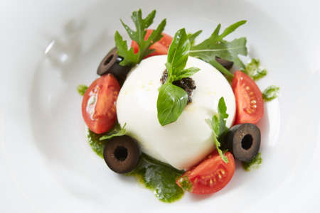 Traditional authentic soft and creamy fresh Italian burrata cheese shaped as white round ball over...