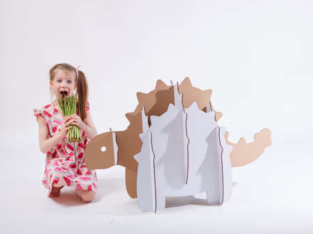 Little dreamer girl playing with a cardboard dinosaur Ankylosaurus. Childhood. Fantasy, imagination.の写真素材