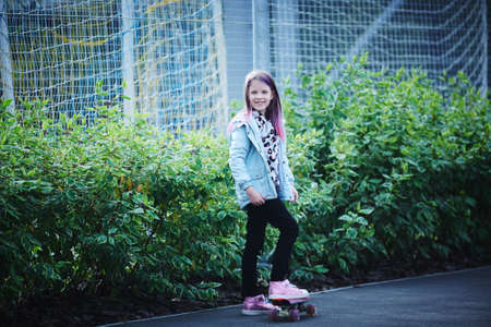 Two pretty little sisters having fun together learning to skateboard outdoorsの写真素材