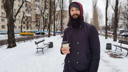 Close up portrait of a bearded young man drinking takeaway coffee. Man drinking coffee