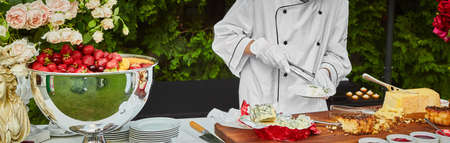 The waiter puts on the plate cheese snacks. Aperitif, catering at a wedding or event.の写真素材