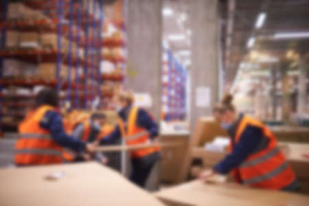 Blur warehouse background. Warehouse worker taking package in the shelf in a large warehouse in a large warehouseの写真素材