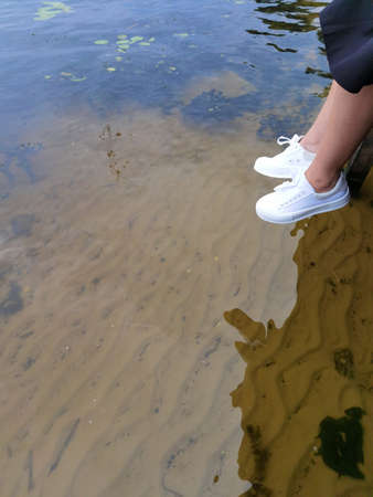 Woman legs above water on a dock, summer relaxの写真素材