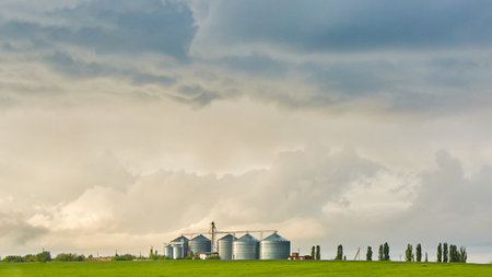 Farm silos at a distant farm at sunset.の写真素材