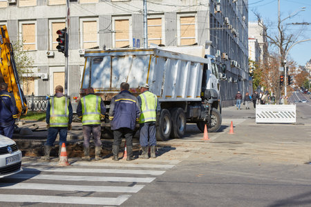Kyiv, Ukraine - October 16, 2022: Utilities are repairing a damaged section of road nearby the Teachers House building on the street near Taras Shevchenko National University where a missile hit.のeditorial素材