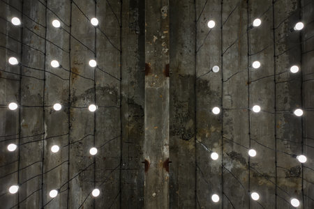 Turned-on white tone light bulbs in lamps lined up under grey painted cement ceiling - rustic and loft style - open space - perspective worm viewの写真素材