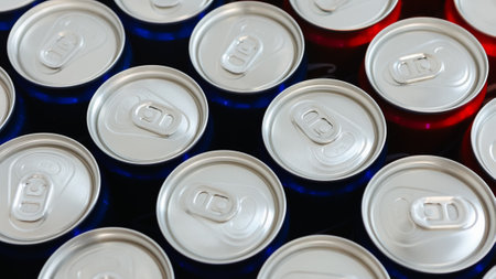 Overhead view of neatly arranged red and blue beverage cans with silver tops, symbolizing...
