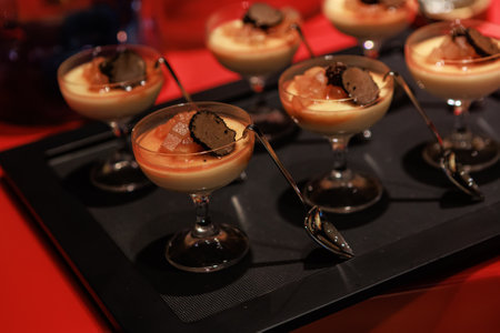 Elegant gourmet dessert served in delicate glassware, featuring a creamy panna cotta base topped...