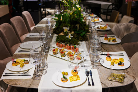 Elegant floral centerpiece with white tulips and lush greenery on a luxurious dining table, ideal...