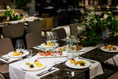 Elegant table decor for luxury dining with floral centerpieces, gourmet appetizers, stylish glassware, and sophisticated table settings ideal for upscale events.の写真素材
