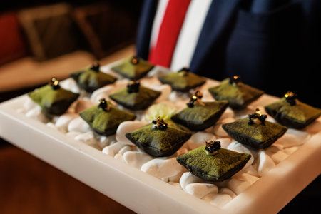 Luxurious matcha-infused dessert with a velvety green coating, elegantly presented on a bed of smooth white stones. Ideal for gourmet food, fine dining, luxury catering, and artistic dessert photographyの写真素材