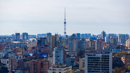 Panoramic aerial view of the Kyiv skyline featuring the iconic TV Tower rising above a dense urban...
