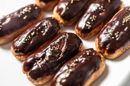 Eight classic eclairs arranged neatly on a white plate.
