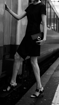 An elegant woman boards a train. A timeless concept for a journey, fashion, and sophisticated departures. Soft focus and grain. Film camera effect. A black and white conceptの写真素材