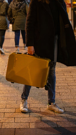 A traveler carries a bright suitcase on a city street. Concept for the modern journey, urban mobility, and a grab and go lifestyle. Soft focus and grain. Film camera effectの写真素材