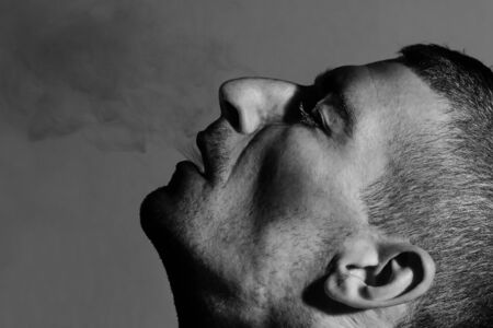 Man exhales smoke