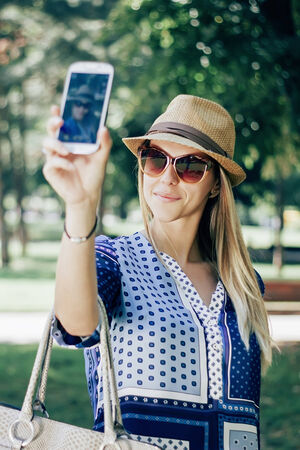 Girl taking a picture of herself outdoorの写真素材