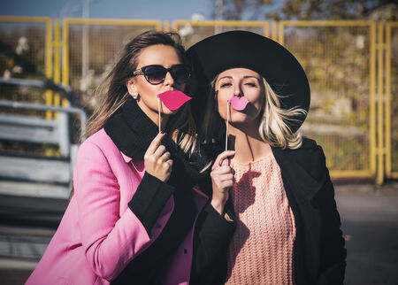 Girlfriends holding fake pink lips