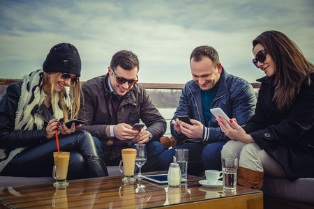 A group of people looking at a cell phone and laughingの写真素材