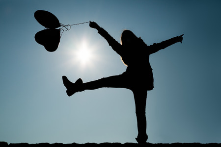 Girlfriends lifting leg and arms in the air while holding balloonsの写真素材