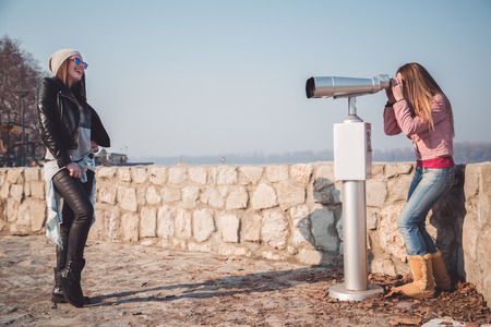 Girl posing in front of binoculars telescopeの写真素材