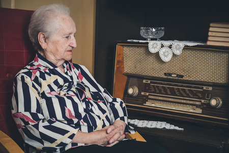 Sad senior woman sitting in a chairの写真素材