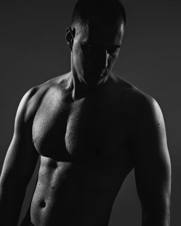 Muscular man posing in shadowの写真素材