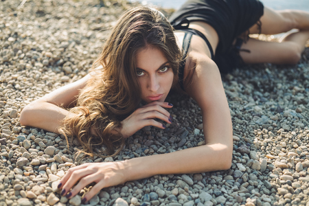 Girl lying on the beach and looking at cameraの写真素材